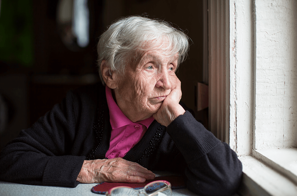 Senior woman looking out the window looking sad