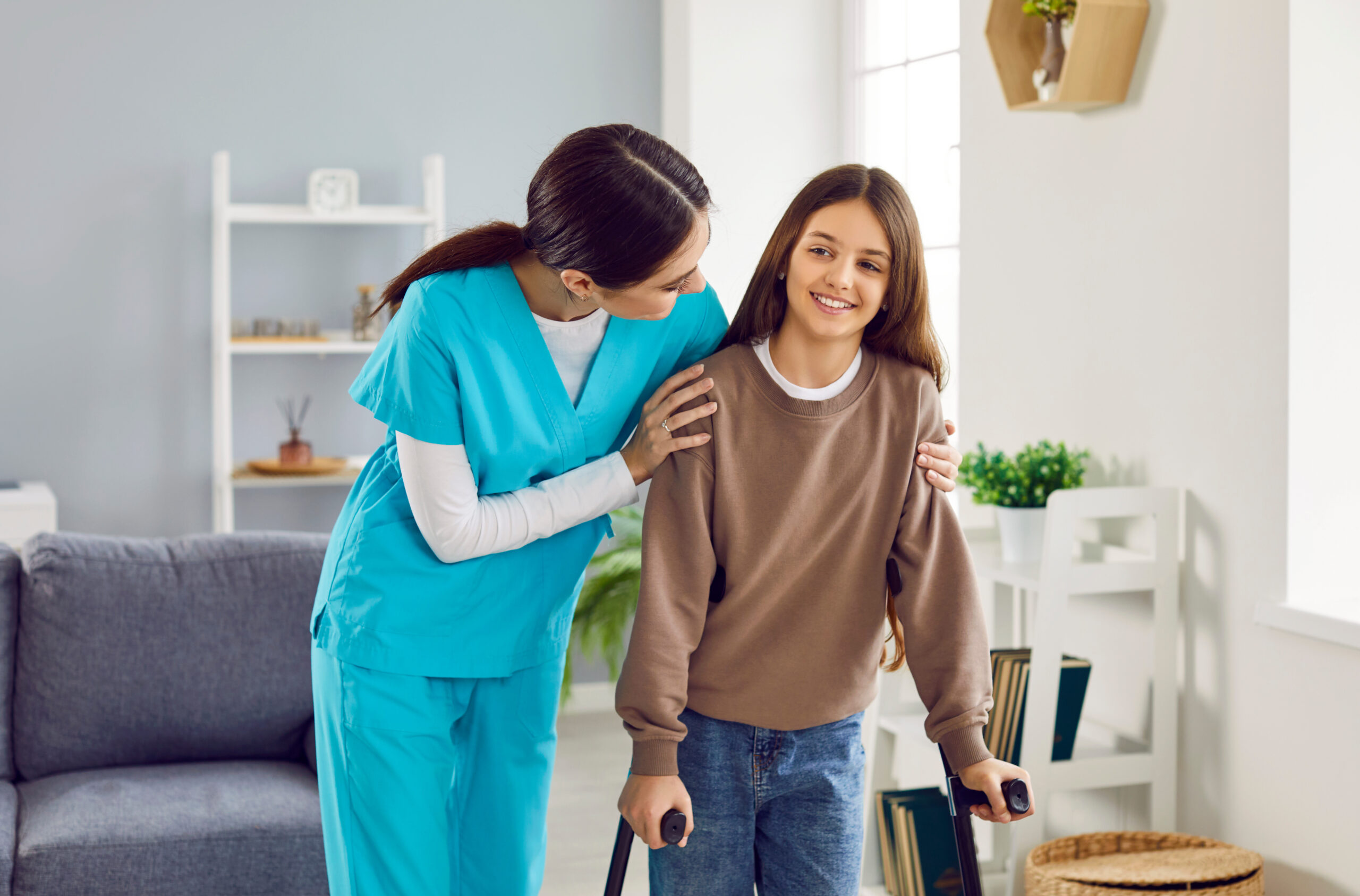 Doctor or nurse helps happy child patient with broken leg walk with crutches at home Pediatric Home Care Toronto